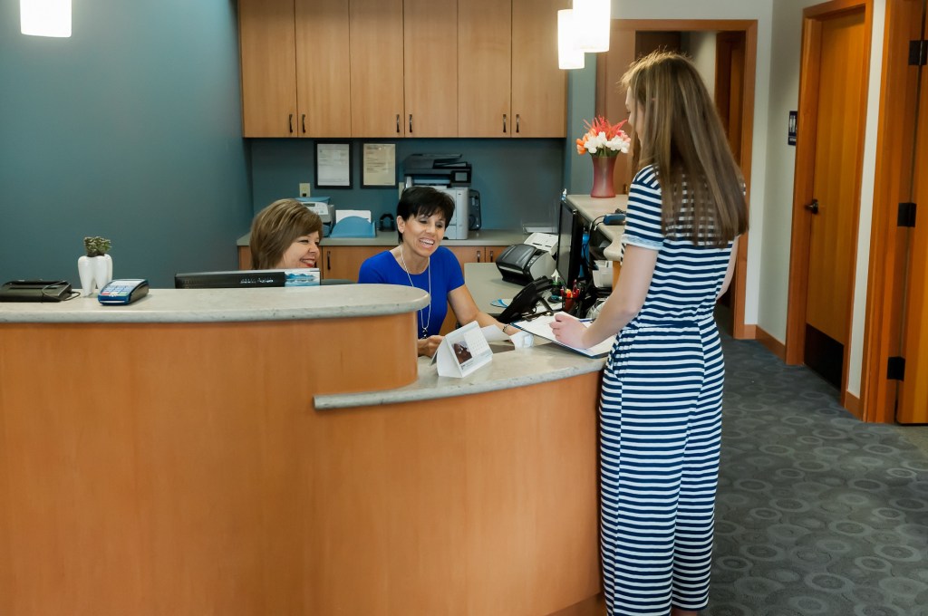 Receptionists and a dental patient at the front desk