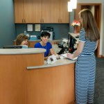 Receptionists and a dental patient at the front desk